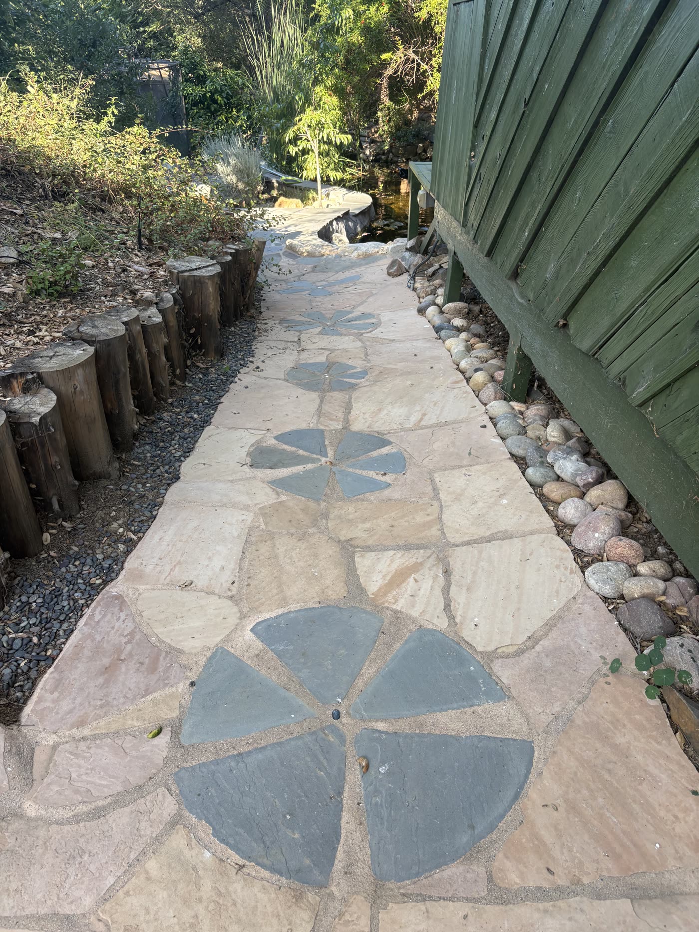 A stone path inlaid with flagstone medallions winding past the office through dappled canyon greenery